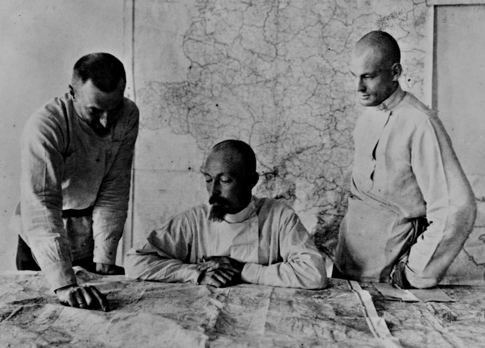 Дзержинский Ф. Э. сидит за столом и просматривает карту военных действий.