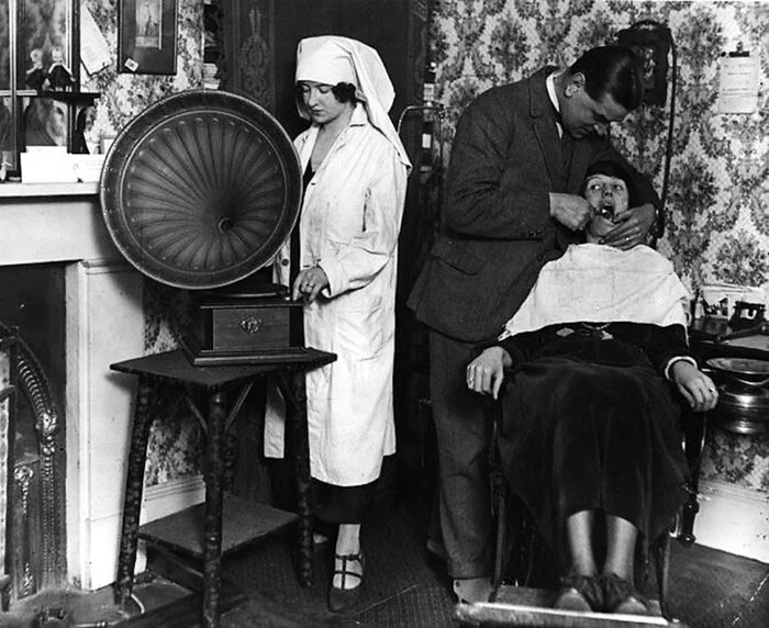 A dentist's assistant starts a gramophone to distract a patient from pain, 1922 - The photo, Black and white photo, 1922, Dentistry, Old photo