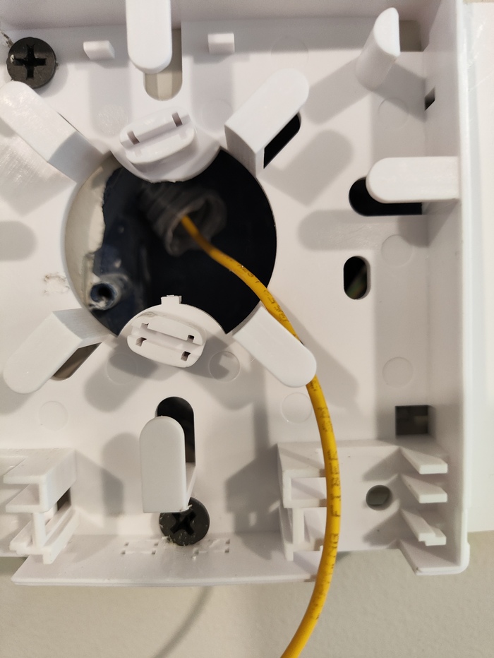 Разобранная пластиковая коробочка которая скрывает дырку в стене с оптическим кабелем