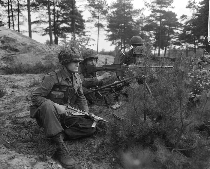 На переднем плане военнослужащий с пистолетом-пулеметом STEN