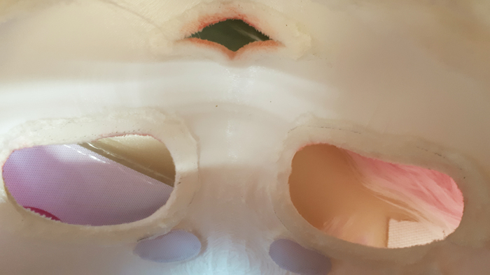 Разровняли натянули и аккуратно проделали отверстия. После чего просто заклеиваем края ткани внутри маски.