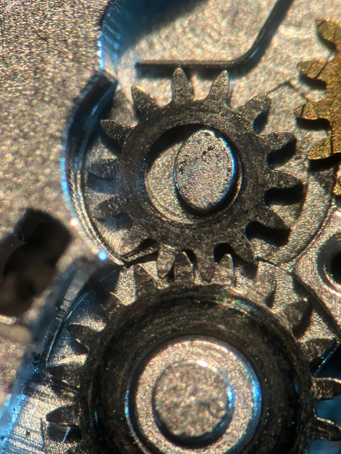 Участок ручного завода часов. Видны обильные следы трения, мелкий сор и старая смазка