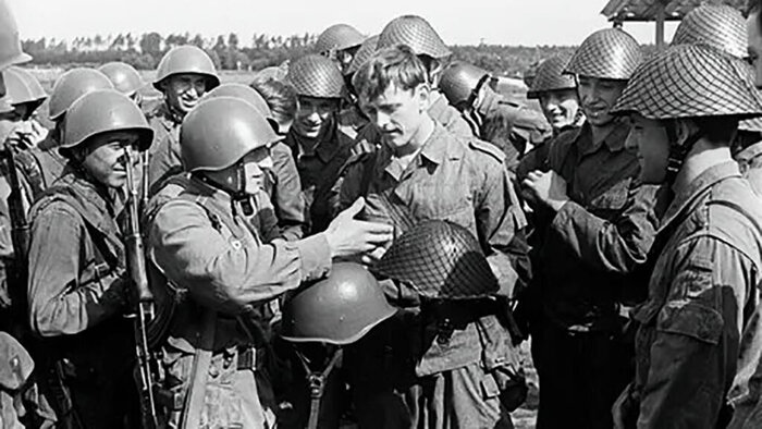 Военнослужащие армий СССР и ГДР знакомятся с особенностями штатных шлемов друг друга (СШ-40 и М54)