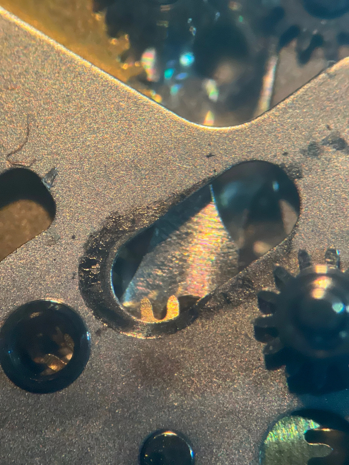 Следы повышенного трения, осколок + мусор под мостом ремонтуара - узел отвечающий как за ручной завод, так и за настройку времени и даты