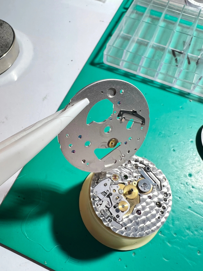 Снял циферблат, за ним снял мост даты и открылся механизм перевода стрелок - ремонтуар, суточное колесо + передаточные колеса, виден барабан. На мосту видны черные следы от повышенного трения
