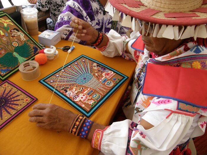 Мастер за изготовлением картины из шерсти. Фото с сайта huichol-artist-yarn-painting.