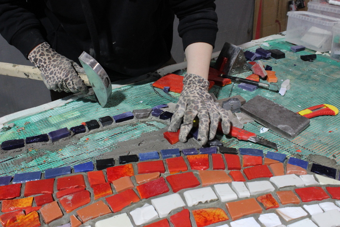 Рабочий стол художника по мозаике. Из основных инструментов молоток для колки смальты, харди, нож, мастихин.