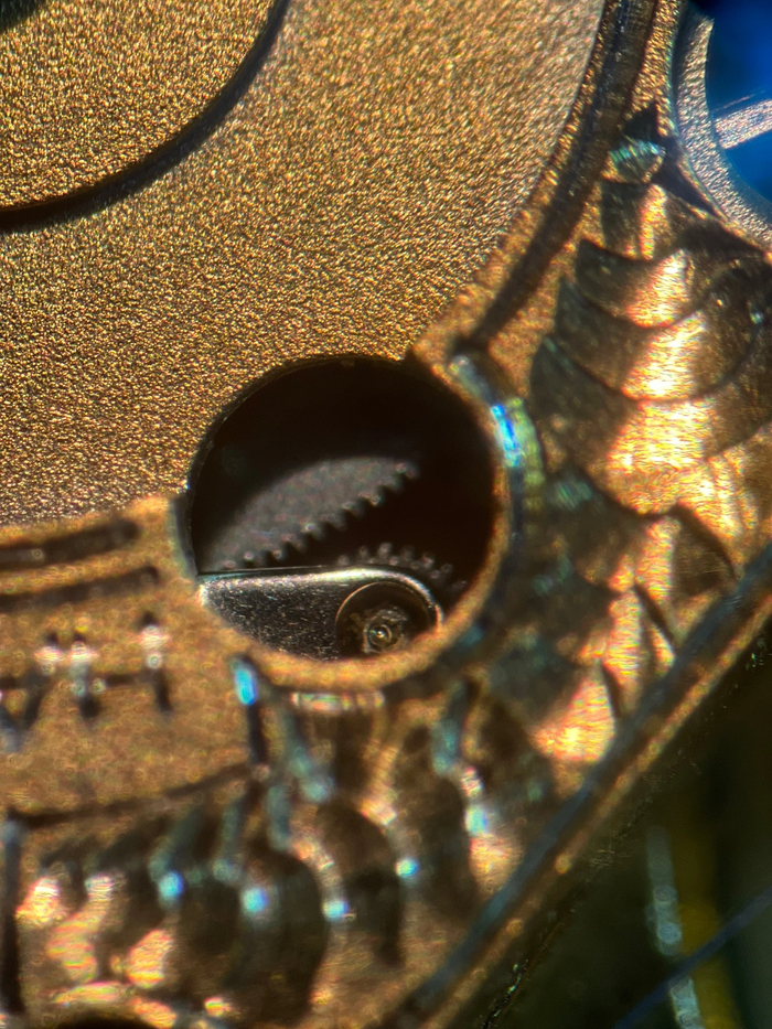 Ось качающейся шестерни с частичками грязи и старой смазки