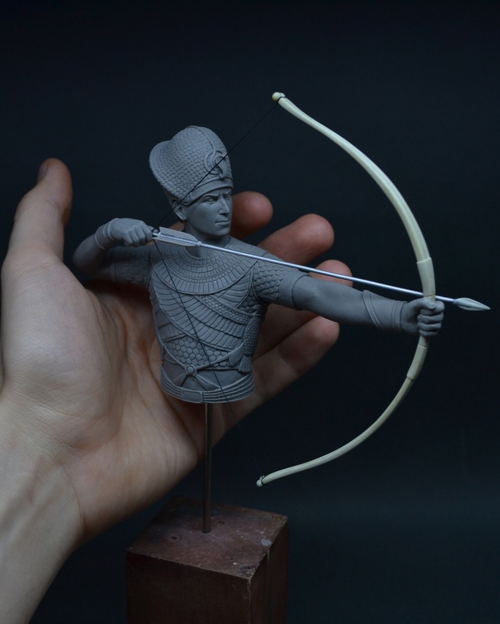 Скульптура фараона на фоне руки скульптора. Для понимания размера миниатюры.