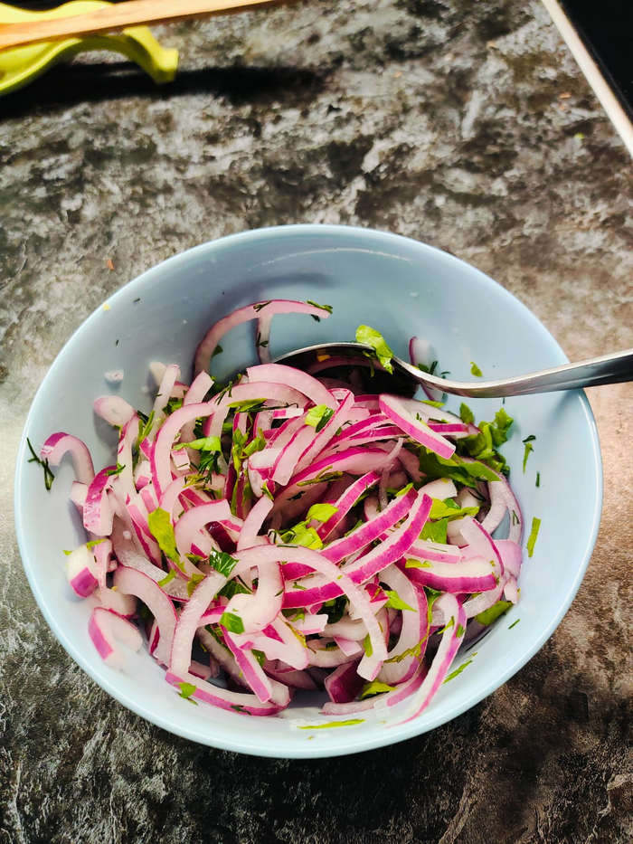 Обливаю лук кипятком, промываю холодной водой, добавляю сахар, соль, яблочный уксус, зелень. Перемешиваю. Всё.