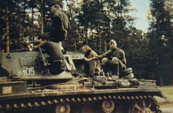 На фотографии танкисты 18-й танковой дивизии вермахта, позади них пленные бойцы РККА на броне танка Pz. Kpfw. III. Лето 1941 года