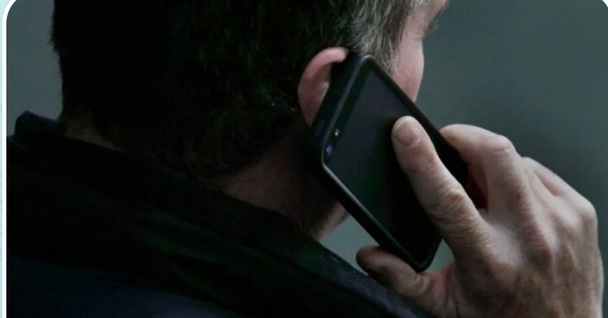 мошенник с телефоном и подозрительным выражением лица