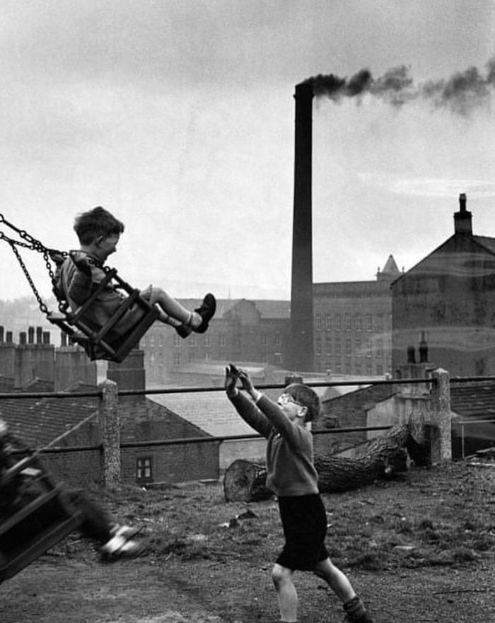 Playing on a swing near factory in Leeds, England, 1955.