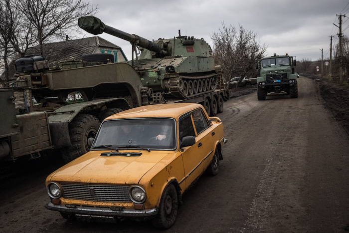 Автомобиль «Лада» проезжает мимо военной транспортной машины с гаубицей в Донецкой области Украины 26 декабря. (Эд Рам для The Washington Post)