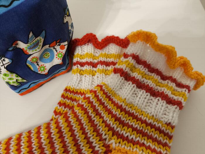 Воланчики на правом и левом носках можно связать разного цвета, придерживаясь общей цветовой гаммы. Здесь красный и желтый воланы и полоски на манжетах тоже красные и желтые, но в разной последовательности