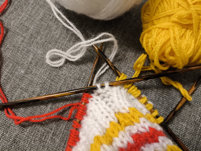 Две белых петли в конце ряда переснимаем на правую спицу и дальше вяжем белой нитью