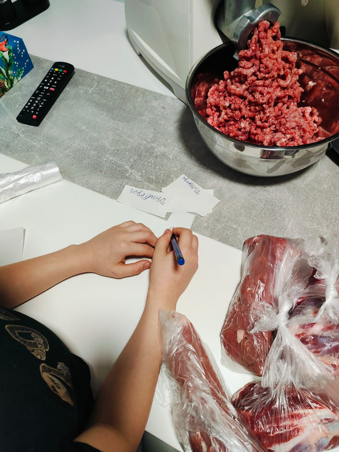 Часть мяса заморожу кусками. Вырезка и поджарка. Мелкий подписывает бирки.