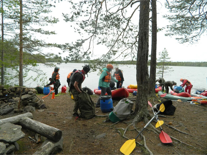 Фото сделанное в походе на байдарках ТаймТриал. Происходит сбор лагеря, где все друг другу помогают. 