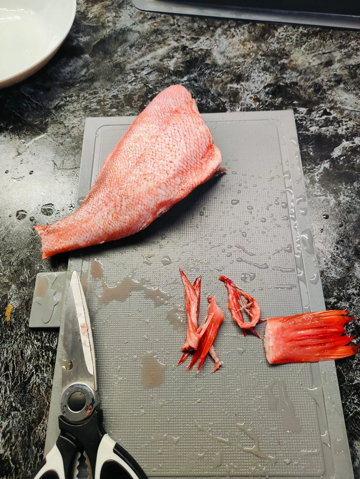 Пока занимался овощами рыба разморозилась. Отрезаю хвост и плавники кухонными ножницами.