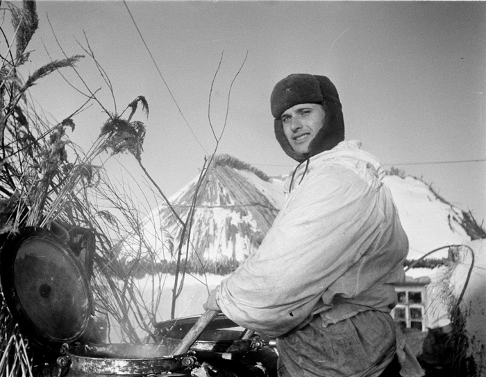 Войсковой повар советской полевой кухни выдает горячую пищу в населенном пункте. Фото - Семен Фридлянд